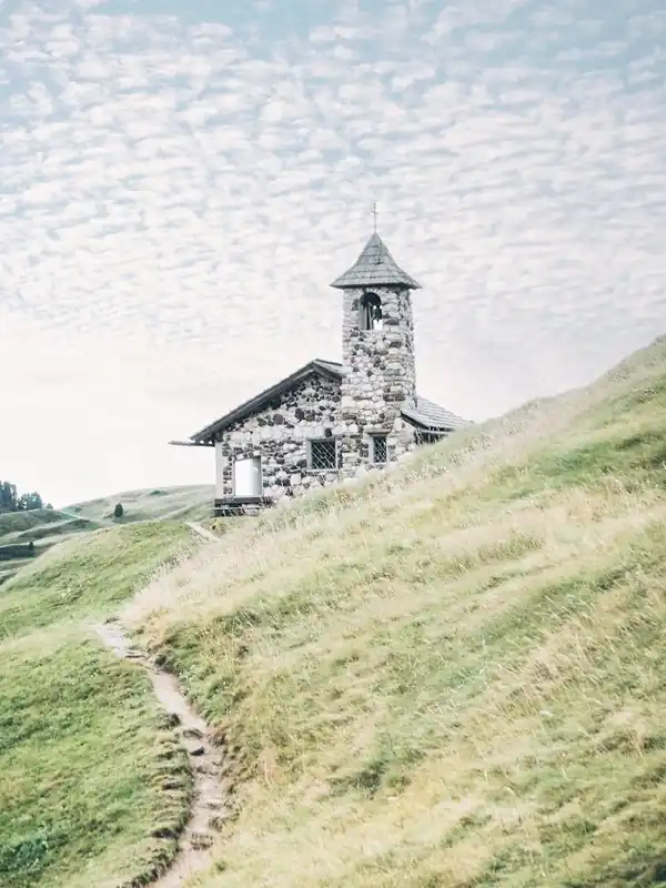 Dolomites, Italy I Stone church on the Seceda mountain surrounded by greenery and its winding path to the authentic rustic architecture of a farmhouse in a nature green aesthetic Alps landscape photography Popular
